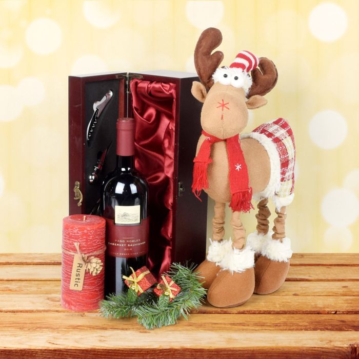 The Holly Jolly Reindeer Gift Set is a delightful way to spread Christmas cheer this holiday season! Featured in this gift set is an adorable reindeer decoration, a wine box with essential wine tools in the lid, a rustic red pillar candle, and a bottle of wine which can be customized or upgraded from our extensive collection